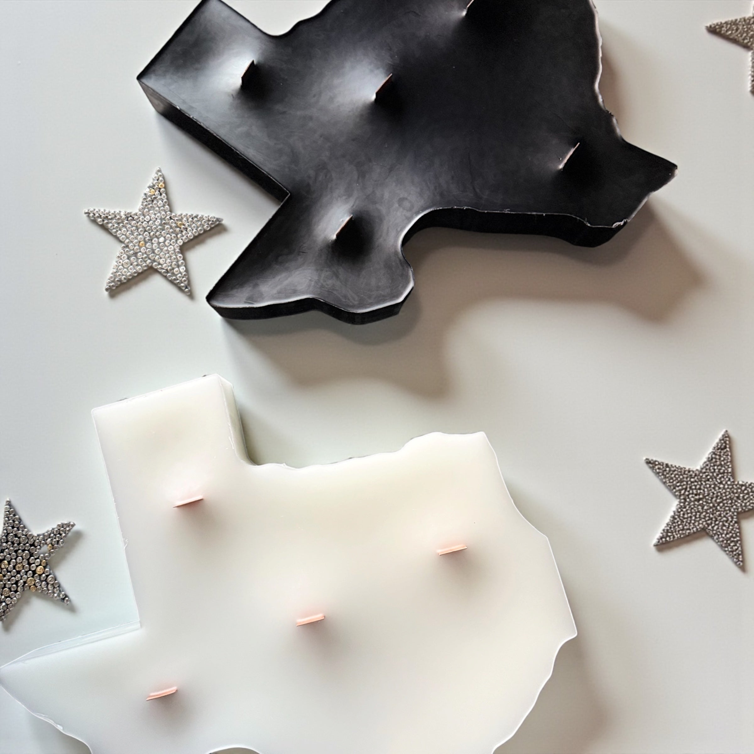 Black and ivory Texas silhouette paraffin pillar candles with wood wicks displayed beside decorative silver stars.